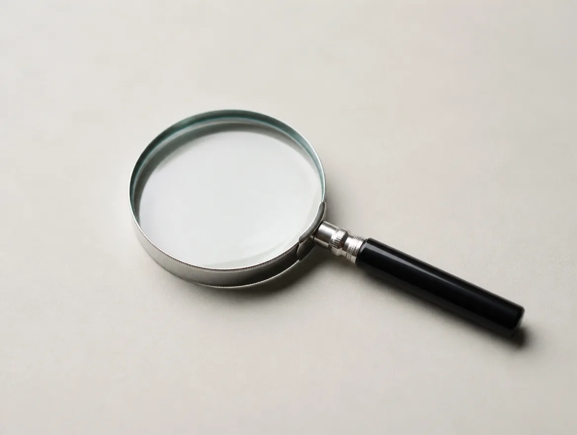 A magnifying glass resting on a plain blank surface with nothing underneath it to find.