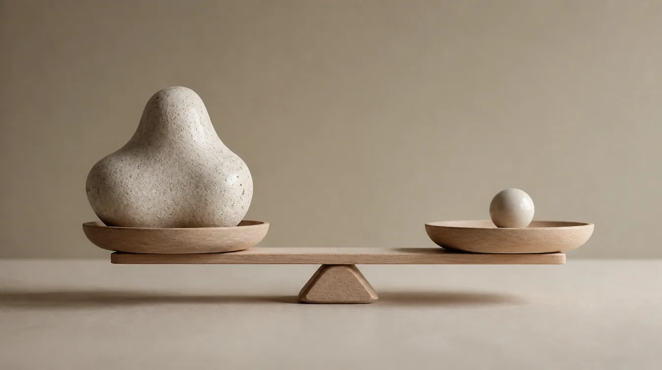 A simple balance scale weighing two objects of different sizes on a plain surface.