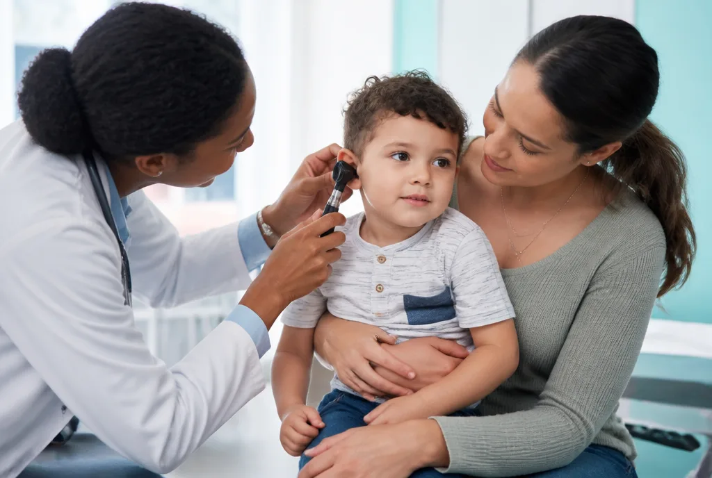 A doctor examining a young child's ear while a parent holds them