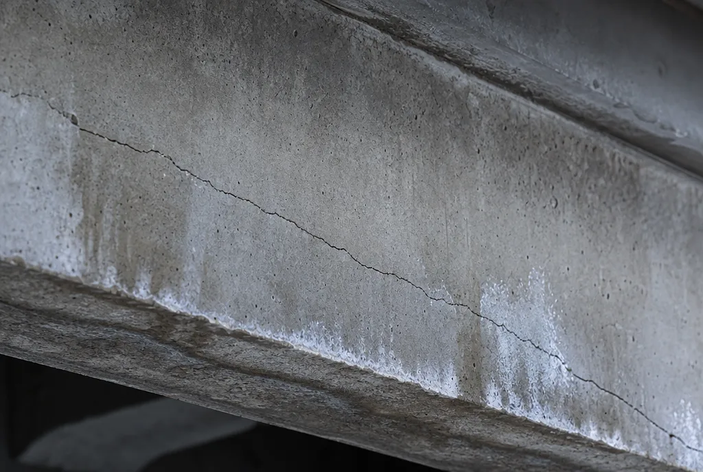 Hairline crack across a grey concrete beam
