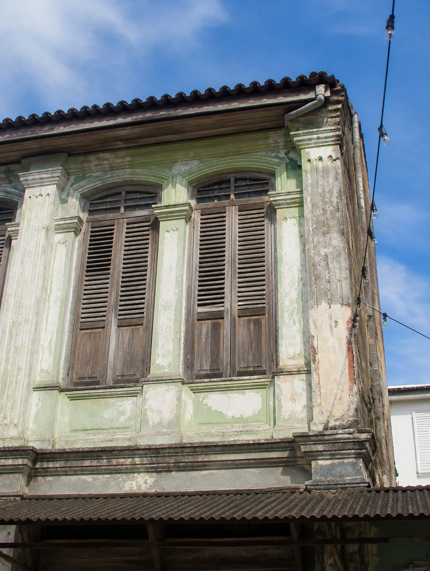 The upper facade of a Penang shophouse with timber louvred shutters