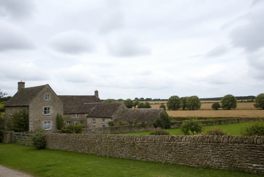A stone farmhouse behind a low wall with open fields beyond, near Uffington
