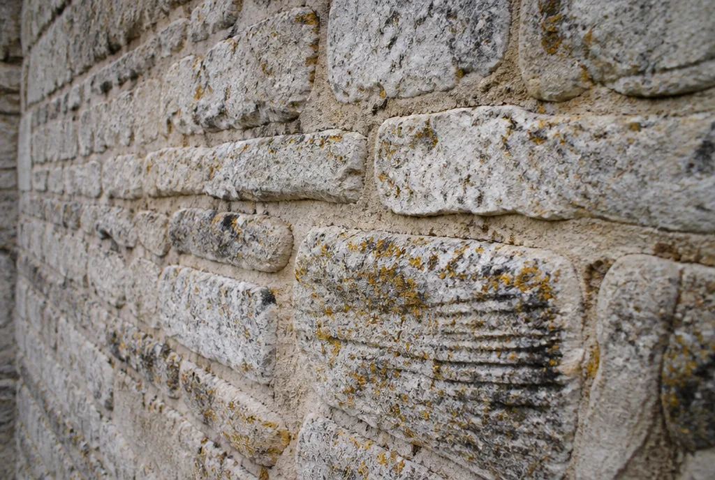 A close view of a limestone wall showing lime mortar joints and lichen