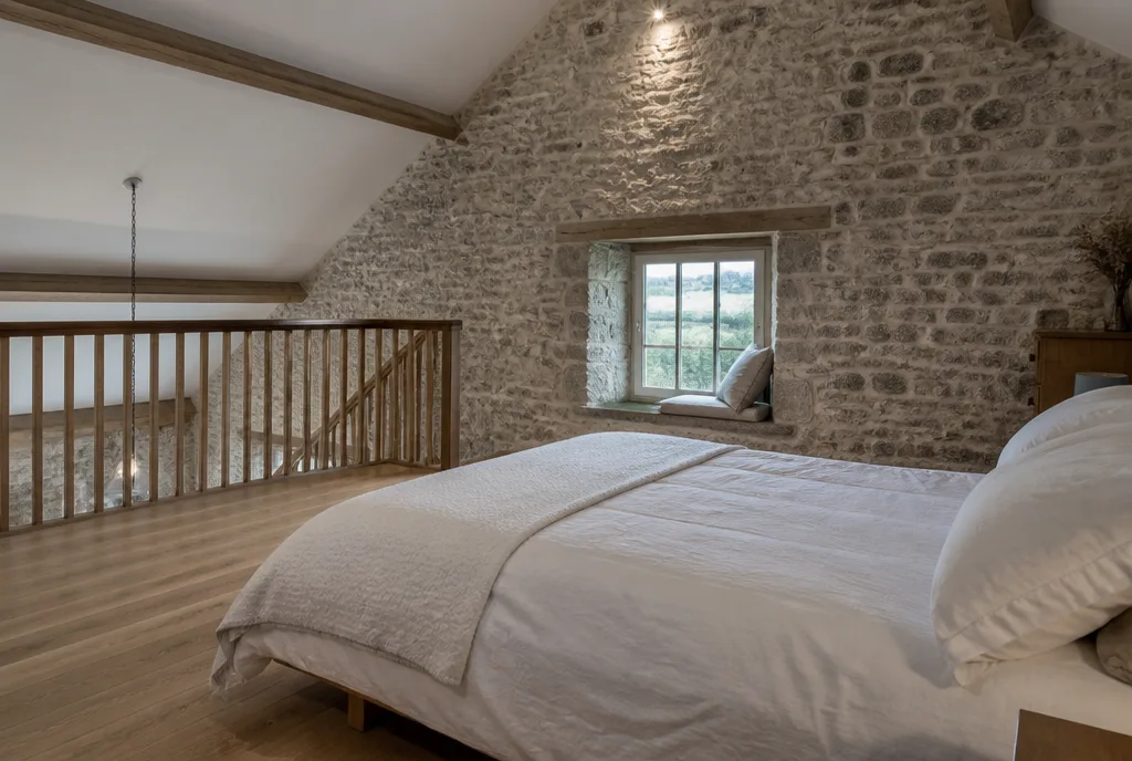 The main bedroom at Barnack on a mezzanine with a stone gable wall and a window seat