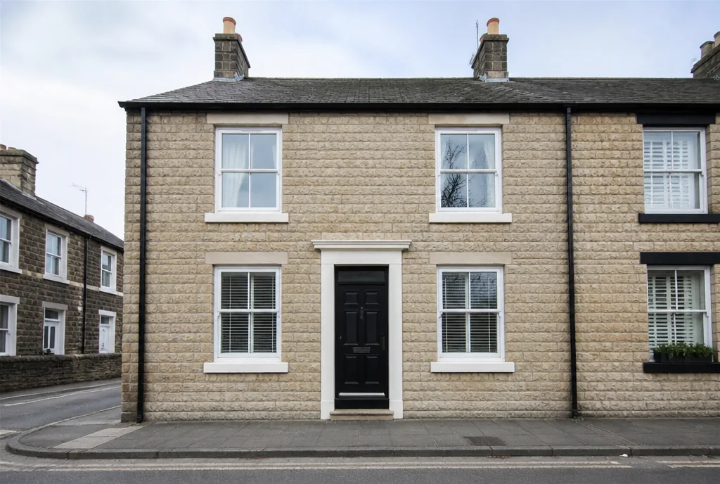 A neat two-bedroom stone terraced house on Burley Road in Oakham with a black front door