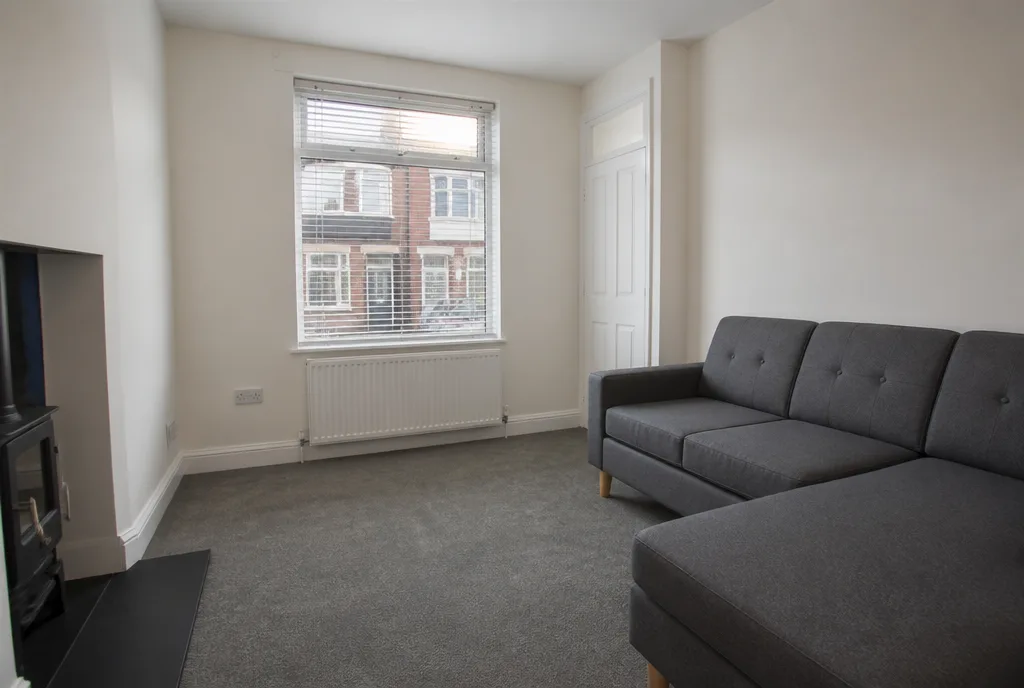 The sitting room of the Oakham rental, freshly painted with a modern grey sofa and a window onto the street