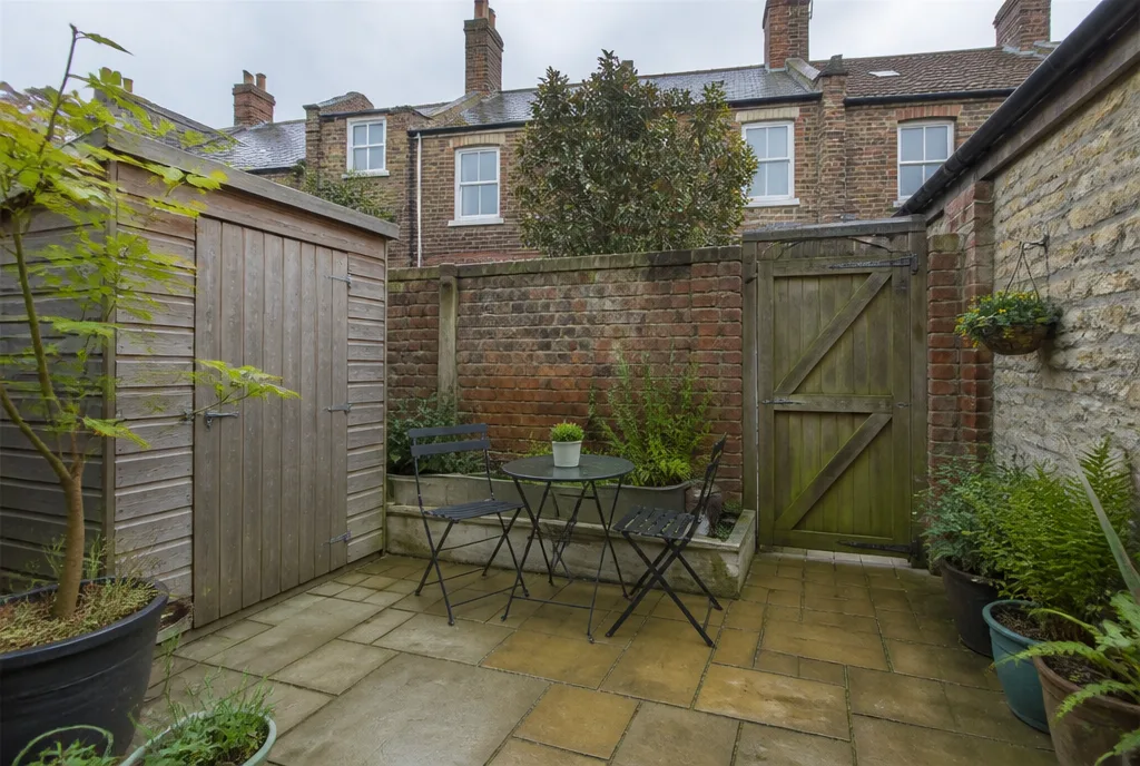 The rear courtyard garden of the Oakham rental with a shed and paved seating area