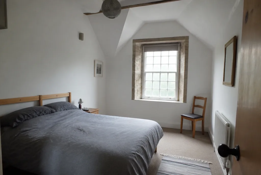The bedroom of the St Paul’s Street apartment under a sloping ceiling with a small stone window