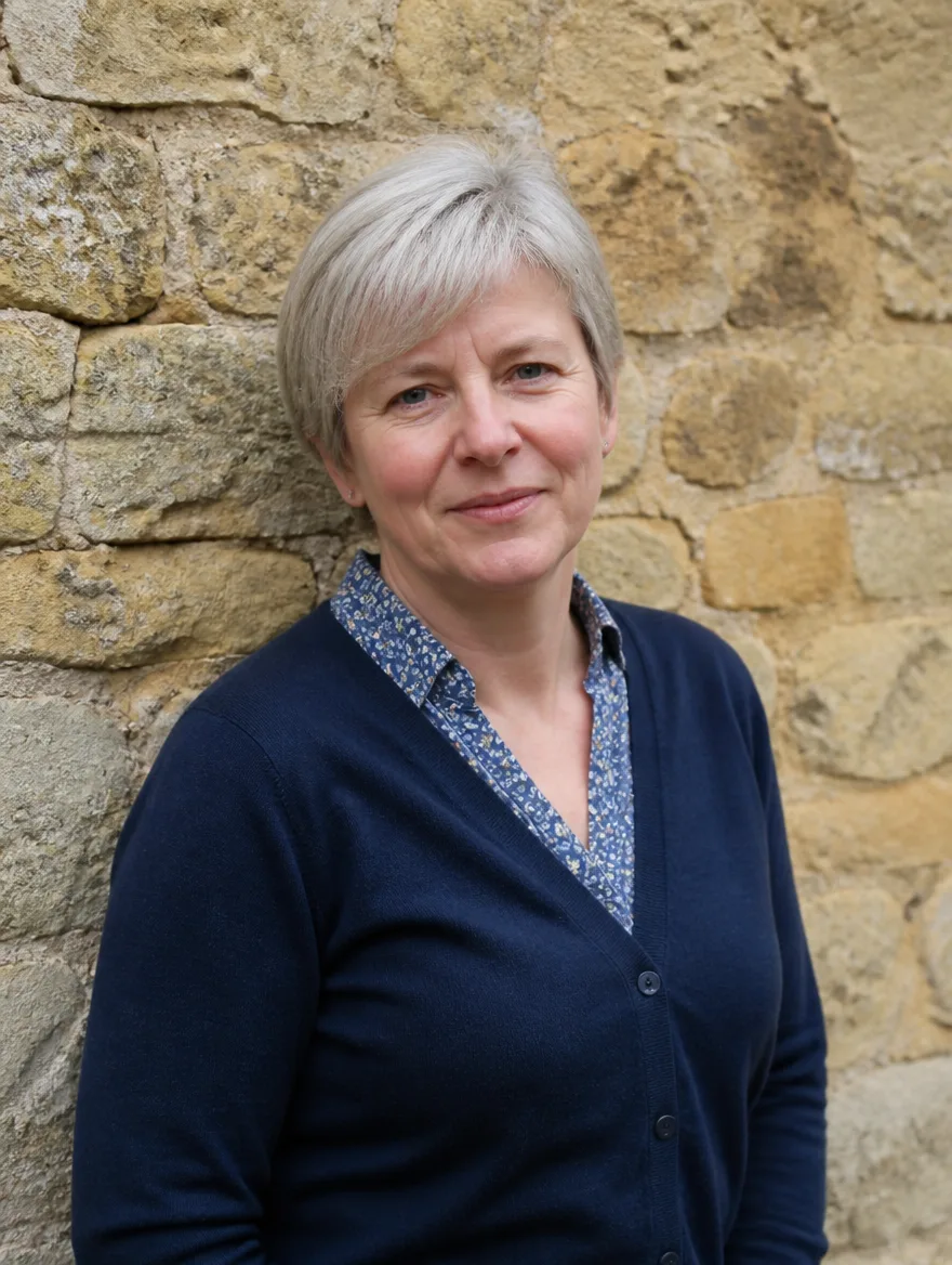 Hazel Pemberton, accounts manager, a woman in her fifties with silver hair and a navy cardigan, photographed against a limestone wall