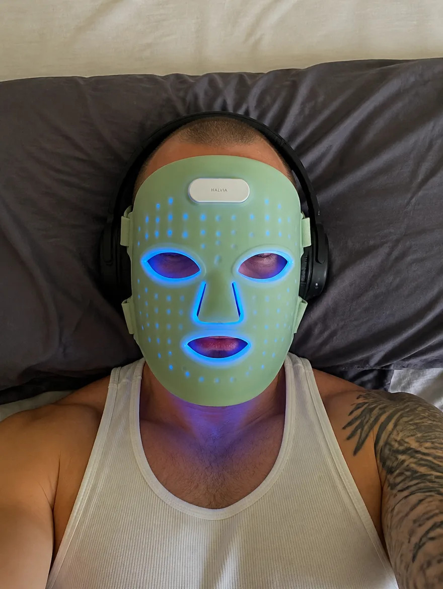 A man lying on a bed wearing the mask glowing blue