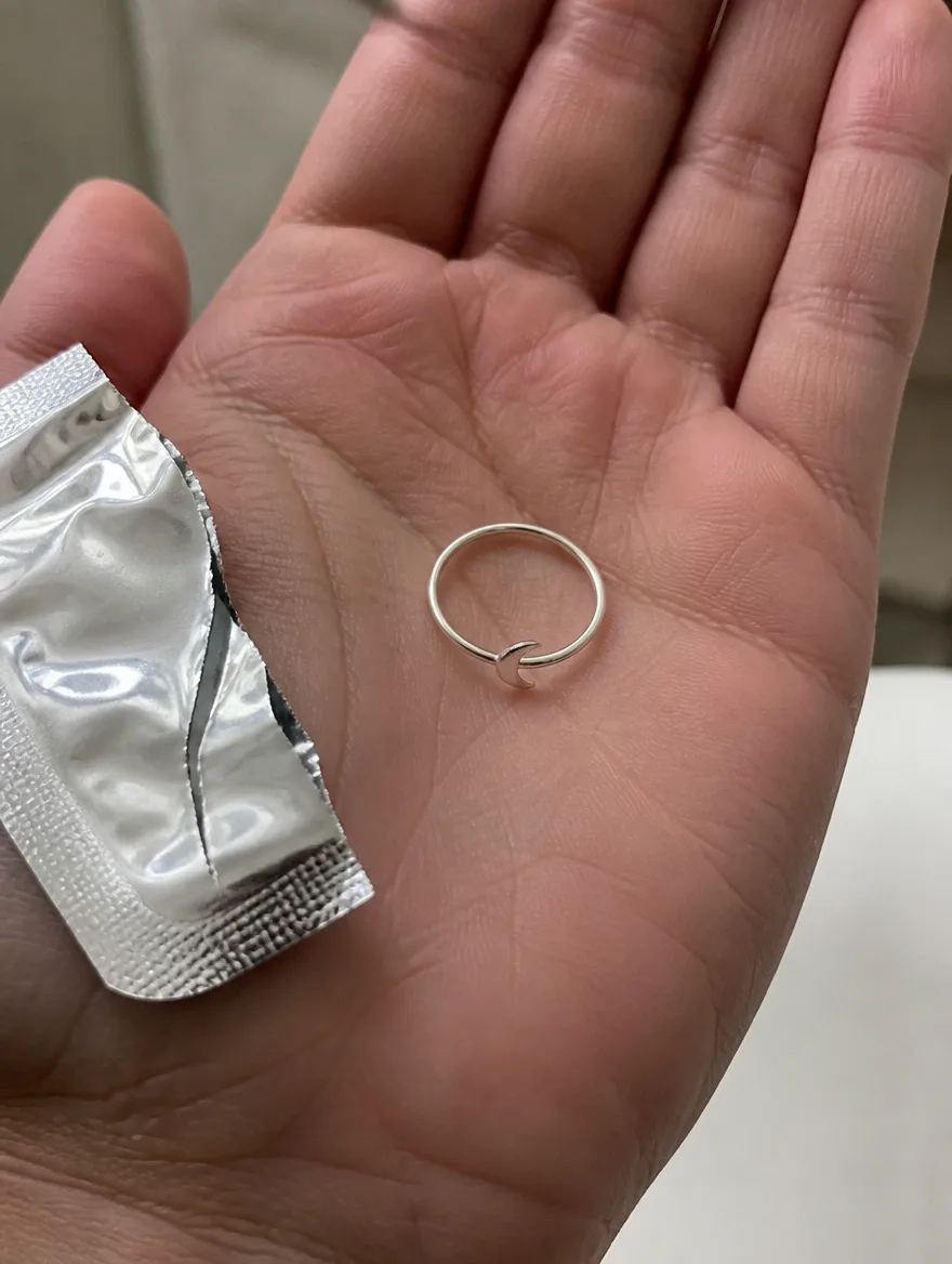 Crescent band in an open palm beside a torn foil pouch